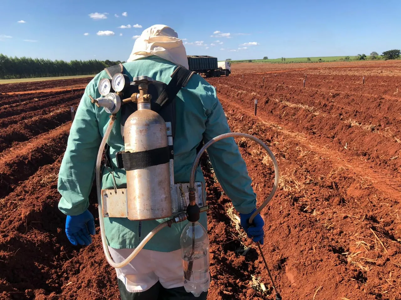 Técnico aplicando tratamento com pulverizador costal a CO₂ em área de ensaio